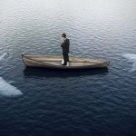 man in boat surrounded by sharks risk fear decision attack threat by peshkova getty