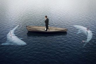 man in boat surrounded by sharks risk fear decision attack threat by peshkova getty