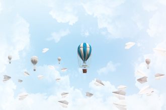 shutterstock 1117048970 colorful balloons flying among paper planes and against a cloudy blue sky